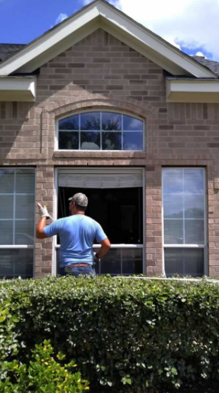 Technician replacing a large picture window on a brick home
