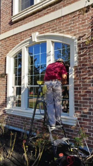 Installer on a ladder working on an arched window